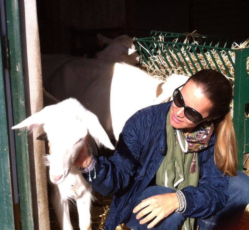 mulher junto a um animal (cabra) fazendo mimos