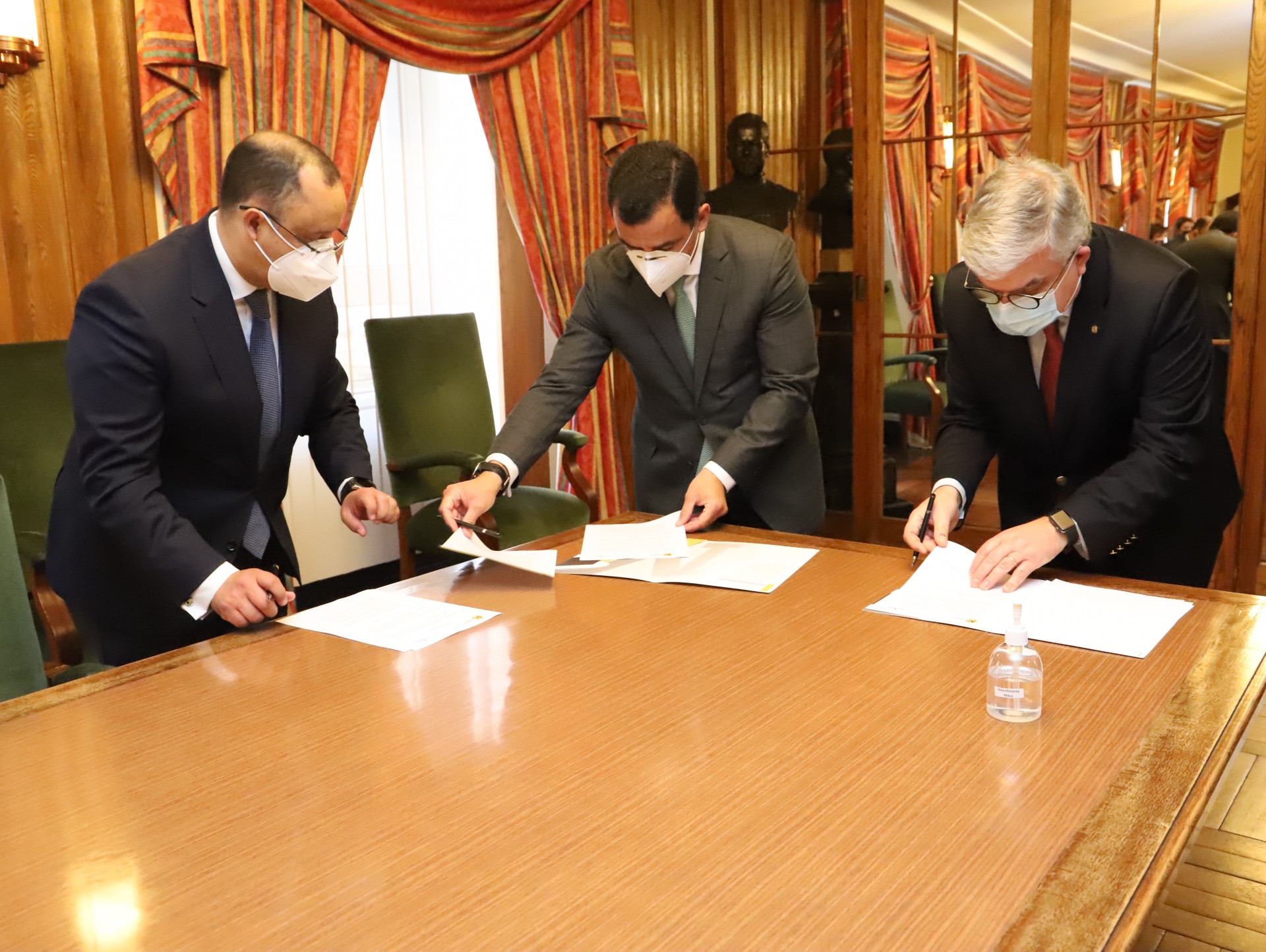 3 homens a assinar documentos