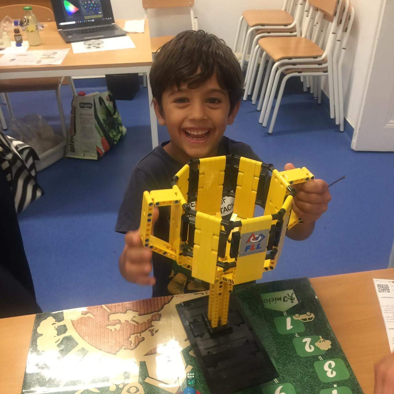 Criança segura uma estrutura amarela de feita de legos