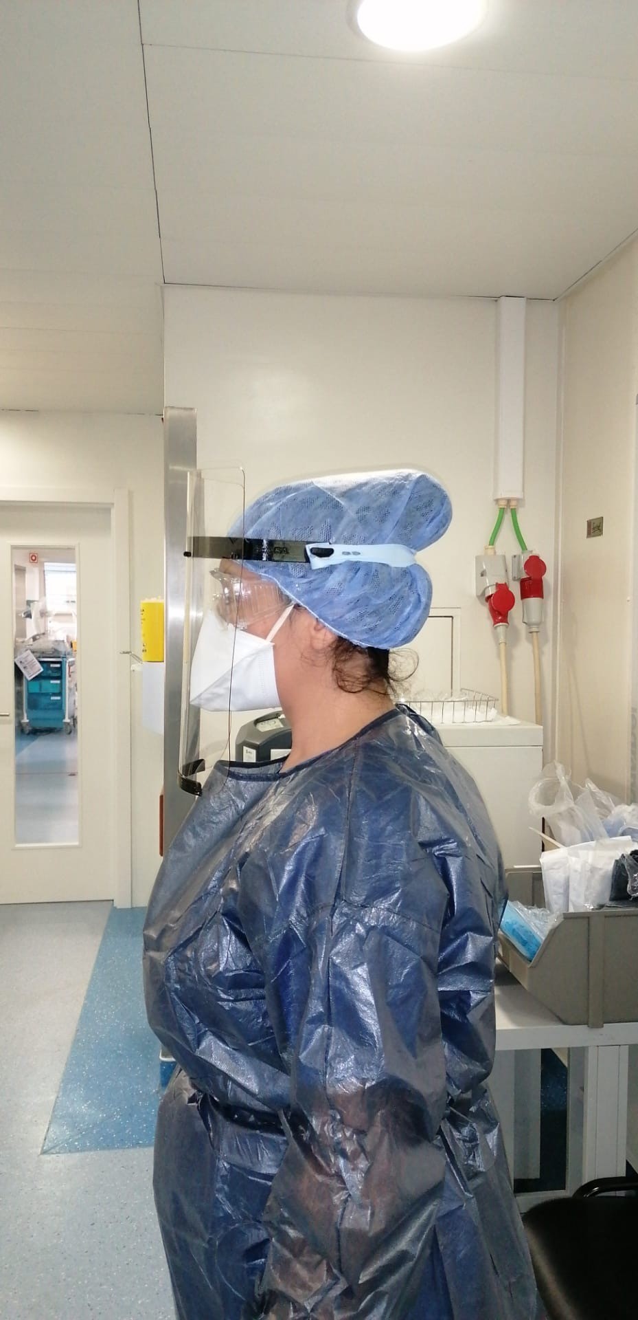 mulher com viseira (máscara) de perfil em ambiente hospitalar