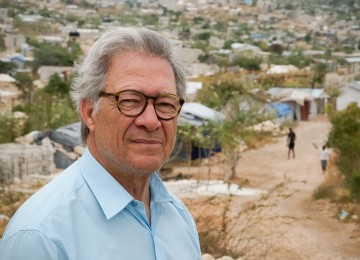 homem de cabelo grisalho sobre paisagem de favelas em África,